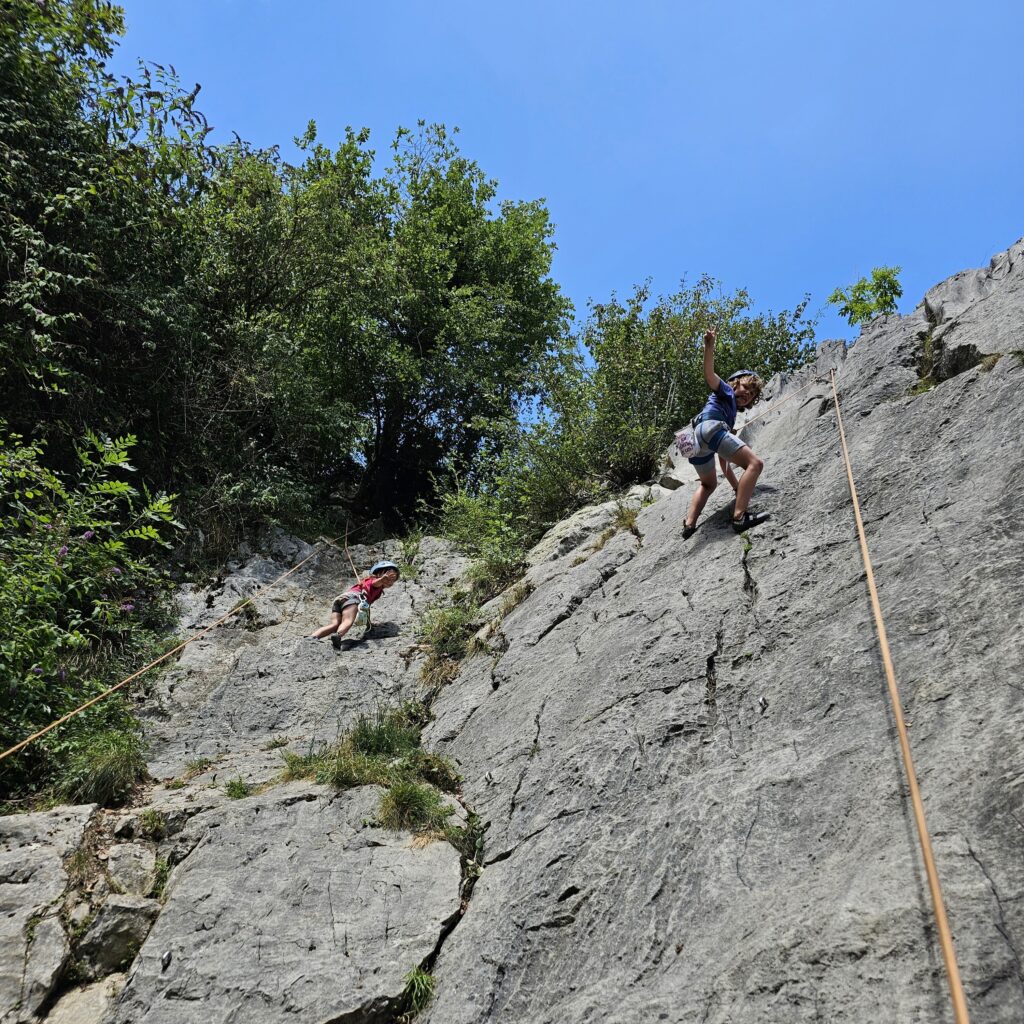 Enfants pratiquant l'escalade sur une falaise.